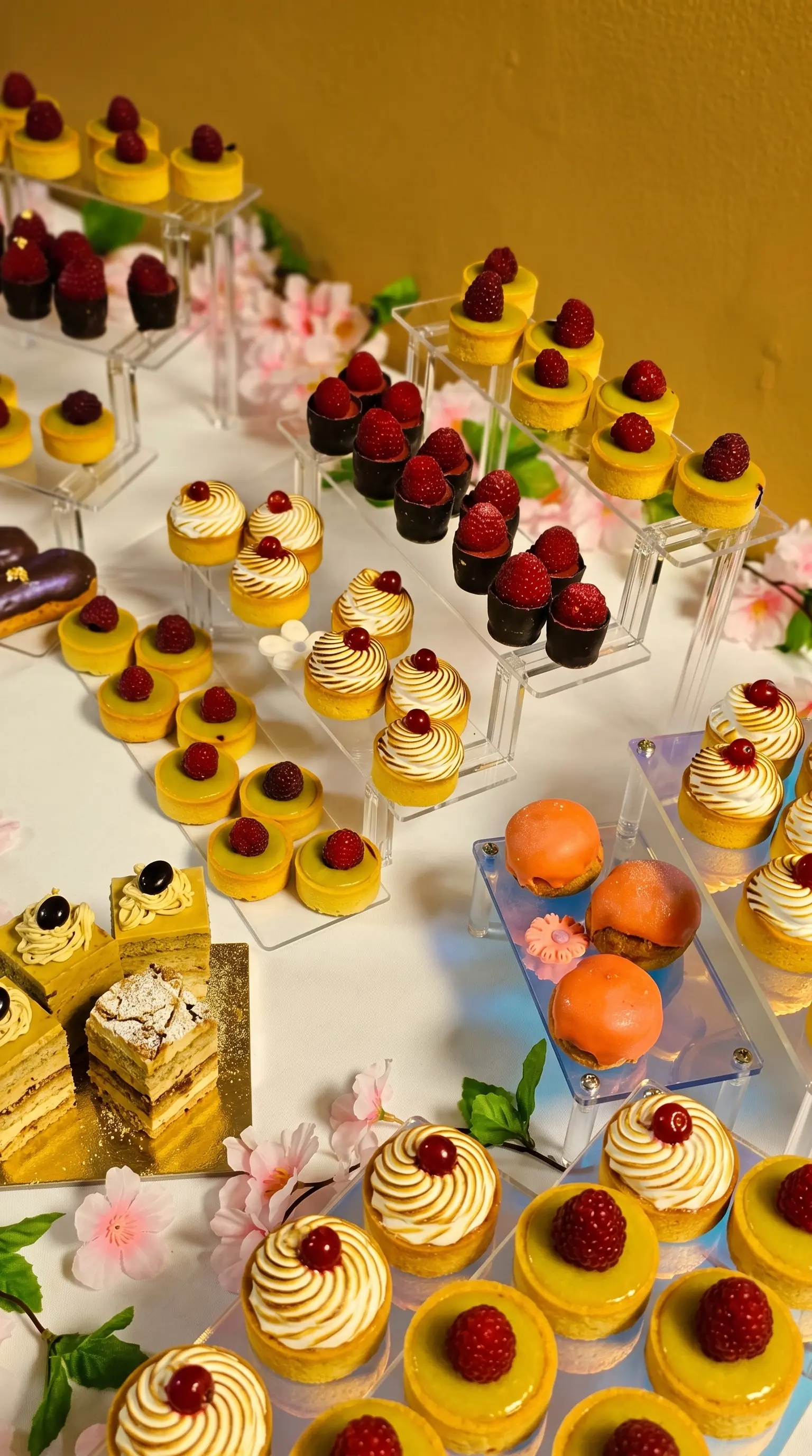 Dessert table close-up with fruit tartlets, raspberry desserts, mini pastries and layered cake pieces